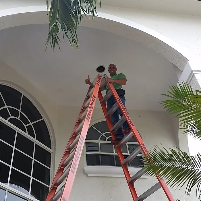 Rey Marrero on a ladder giving a thumbs up after a job